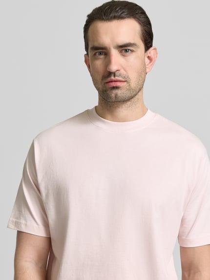 Männermodel trägt Regular Fit T-Shirt aus reiner Baumwolle von MCNEAL in zartem Rosa, Rundhals, kurzärmelig, Nahaufnahme Oberkörper.