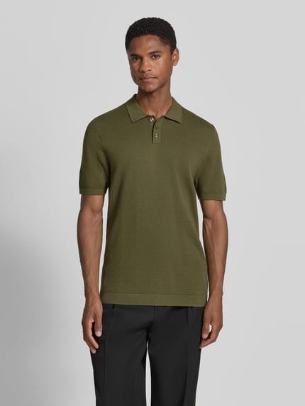 Męski model nosi Slim Fit Poloshirt mit kurzer Knopfleiste Modell 'TRITON' von Drykorn z czystej bawełny, krój slim fit, kolor oliwkowy, przód, ujęcie całej sylwetki.
