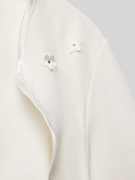 Mädchen trägt Regular Fit Bolero mit floralen Applikationen von Weise, weißer Baumwoll-Mix, Detailaufnahme Schulterbereich.