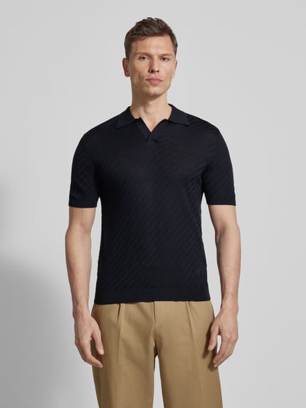 Männermodel trägt Slim Fit Poloshirt mit Lyocell-Anteil von Emporio Armani in Dunkelblau, Strick-Optik, Kurze Ärmel, Ganzkörperansicht von vorne.