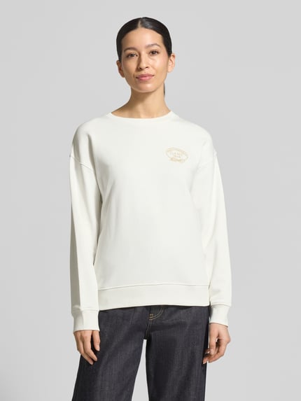 Frauenmodel trägt Sweatshirt mit Label-Stitching und Rundhalsausschnitt von Gant aus weißer Baumwolle im Loose Fit, gerippte Bündchen, Ganzkörperansicht von vorne.