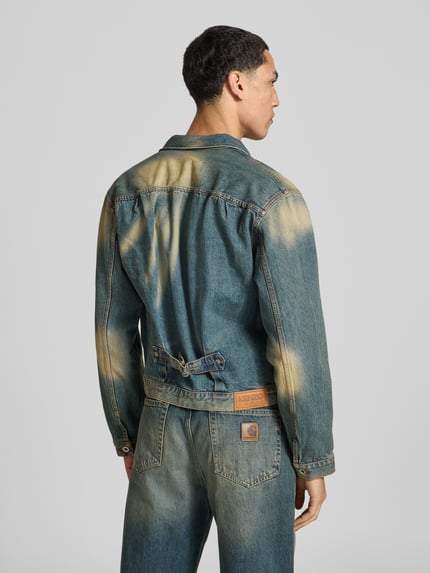Mężczyznamodel nosi Regular Fit Jeansjacke aus Baumwolle von KENZO z Efektem znoszenia i naszywaną brustaszą, kolor niebieski z beżowymi przetarciami, Długość tyłu w rozmiarze M: 58 cm, Szerokość ramion w rozmiarze M: 48 cm, Długość rękawów w rozmiarze M: 63 cm, Ganzkörperansicht Rückansicht