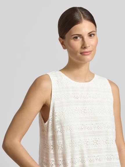 Vrouwenmodel draagt Blusentop aus Spitze mit Rundhalsausschnitt van comma, regular fit, katoenmix, wit met kant, detailopname bovenlichaam.