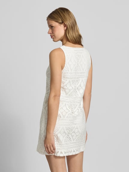 Frauenmodel trägt körpernahes Freizeitkleid aus Baumwoll-Mix Modell 'BONNIE' von Pieces in Unifarbe Weiß mit Strukturmuster, Mini-Länge, breite Träger, U-Boot-Ausschnitt, Ganzkörperansicht Rückansicht.
