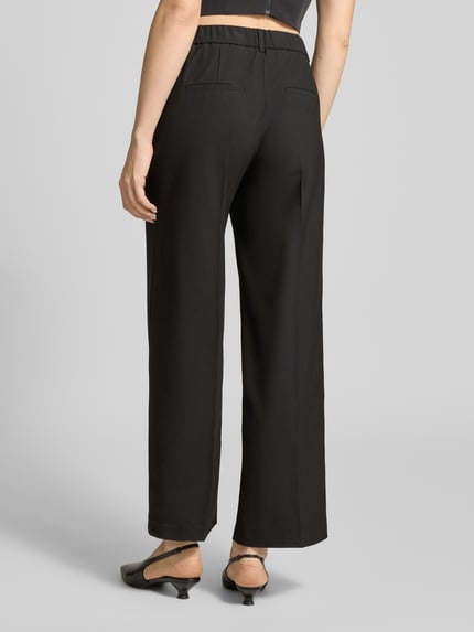 Frauenmodel trägt Wide Leg Stoffhose mit Bügelfalten von s.Oliver BLACK LABEL, Optik: Unifarben, elastischer Bund, Ganzkörperansicht Rückansicht.