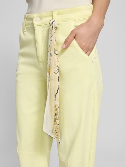 Vrouwenmodel draagt Hose mit Tuch Modell 'ORELIE' van Cambio in lichtgeel, lyocell-katoenmix met stretch, losse fit, Franse steekzakken, detailopname heup.