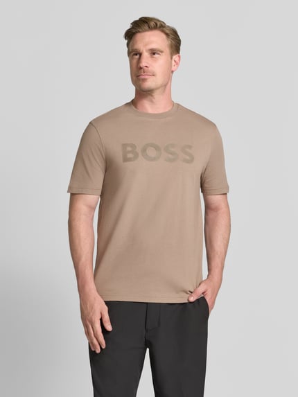 Męski model prezentuje t-shirt krój regular fit z czystej bawełny, model 'TS_STRUCTURE LOGO 1027473' od BOSS Green, kolor beżowy, matowa faktura, widok całej sylwetki z przodu.