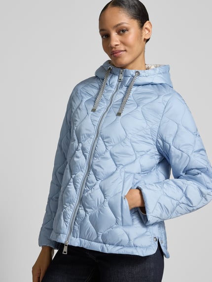 Frauenmodel trägt hellblaue Steppjacke mit Kapuze und Zweiwege-Reißverschluss von Fuchs Schmitt, Regular Fit, Nahaufnahme Oberkörper.