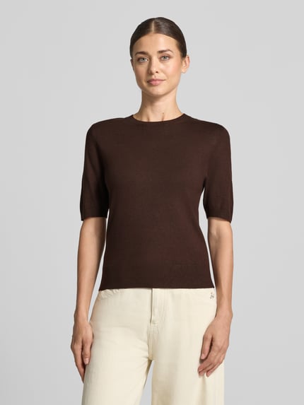 Frauenmodel trägt Regular Fit Pullover aus Viskose-Mix von s.Oliver RED LABEL in Dunkelbraun zu heller Hose, Ganzkörperansicht von vorne.