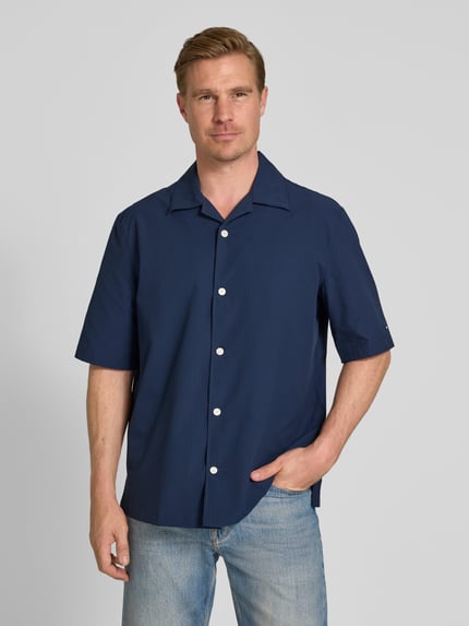 Męski model nosi Relaxed Fit Freizeithemd aus Seersucker-Material von Tommy Hilfiger, granatowy wzór allover, krótkie rękawy, kellerfalte z tyłu, widok całej sylwetki z przodu.