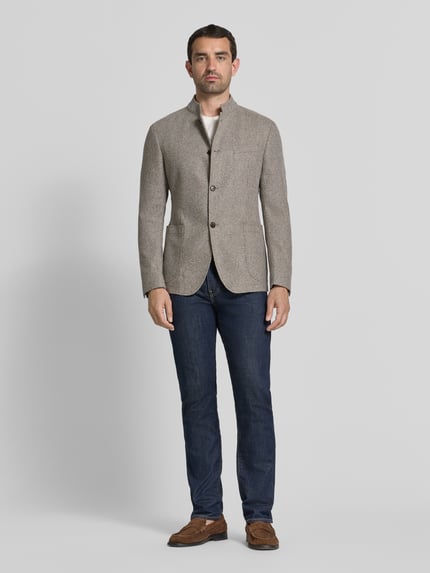 Männermodel trägt Regular Fit Sakko mit Stehkragen Modell 'Hiro' von JOOP! COLLECTION aus Baumwoll-Mix, graue Textur, Ganzkörperansicht von vorne. Rückenlänge bei Größe 50: 73 cm, Schulterbreite: 44 cm, Ärmellänge: 64 cm, durchgängige Knopfleiste, aufgesetzte Taschen.