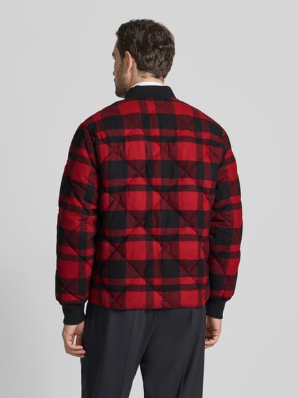 Männermodel trägt Daunenjacke mit Druckknopfleiste von Polo Ralph Lauren, Baumwoll-Mix, kariert in Rot und Schwarz, Ganzkörperansicht Rückansicht.