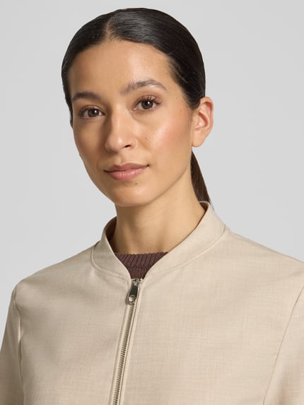 Frauenmodel trägt Regular Fit Blouson mit Viskose-Anteil von s.Oliver BLACK LABEL, efekt: jednolity kolor, melanż, krój regular fit, kształt kołnierza: kołnierz college, zapięcie: zamek błyskawiczny, rękaw: długi rękaw, nakładana boczna kieszeń, wykończenie materiału: batyst, materiał: mieszanka materiałów z dodatkiem wiskozy, kolor beżowy, gładka faktura. Nahaufnahme górnej części ciała.