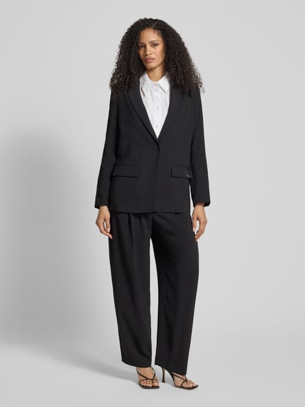 Frauenmodel trägt Relaxed Fit Blazer mit Reverskragen von ARMANI EXCHANGE in Schwarz mit Pattentaschen, Knopfverschluss, Ganzkörperansicht von vorne.