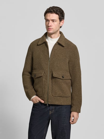Männermodel trägt Hemdjacke mit Zweiwege Reißverschluss von Selected in Braun, Umlegekragen, Pattentaschen, Jeans, Ganzkörperansicht von vorne.
