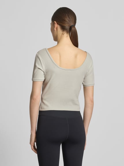 Frauenmodel trägt Cropped T-Shirt aus Lyocell-Mix Modell 'Circe' von Guess Activewear in Beige, gerippte Textur, Rückenansicht, Ganzkörperansicht