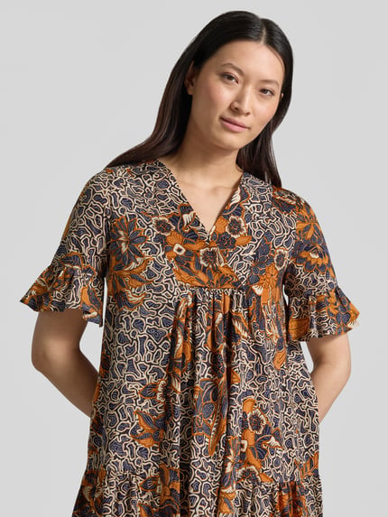 Frauenmodel trägt A-Linien Kaftankleid aus reiner Baumwolle Modell 'FUOCO' von Weekend Max Mara, Optik: Allover-Muster, Passform: A-Linie, Midi-Länge, Rundhals, Ärmelform: Kurzarm mit Volants, Materialverarbeitung: Jersey, Farbe Orange-Blau, Nahaufnahme Oberkörper.