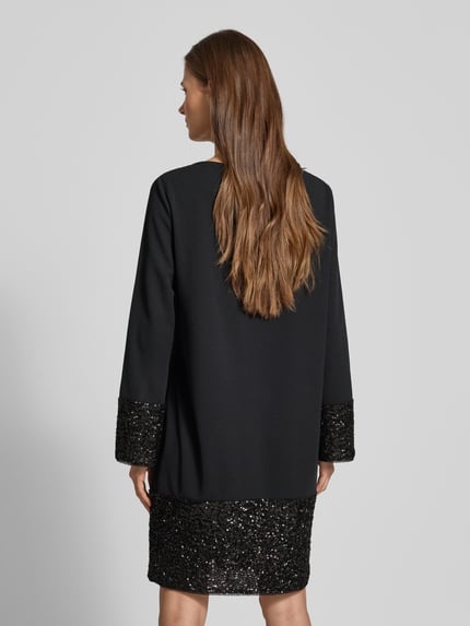 Vrouwenmodel draagt Relaxed Fit Mini-jurk met pailletten van s.Oliver BLACK LABEL, look effen, minilengte, boothals, lange mouw, zonder sluiting, applicatie pailletten, geheelopname rugaanzicht.