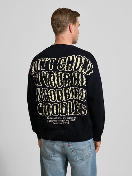 Męski model nosi Strickpullover mit gerippten Abschlüssen Modell 'Kurt' od WOODBIRD, czarny sweter z bawełnianej mieszanki, luźny krój, widok całej sylwetki z tyłu.