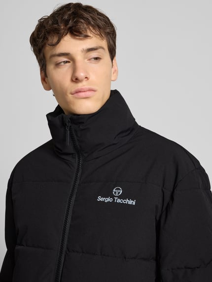 Männermodel trägt schwarze Steppjacke mit Stehkragen Modell 'NILO' von SERGIO TACCHINI, Material-Mix mit Stretch-Anteil, Nahaufnahme Oberkörper.
