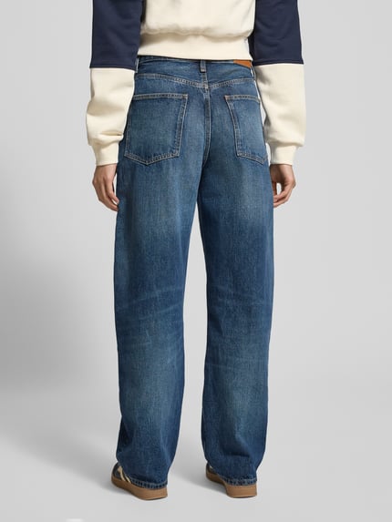 Frauenmodel trägt Tapered Fit Jeans aus reiner Baumwolle von Tommy Hilfiger in Denim-Optik mit Label-Patch und Nieten, Ganzkörperansicht Rückansicht