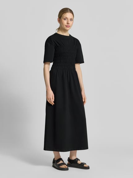 Frauenmodel trägt Midikleid mit Smok-Details von Jake*s Casual, reine Baumwolle, tailliert, schwarz, Ganzkörperansicht von vorne.