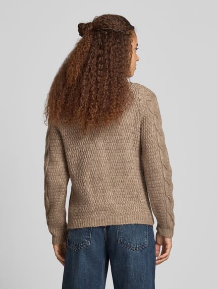 Frauenmodel trägt Cardigan mit Zopfmuster-Strickoptik von PIECES in melange-beige, gerippte Abschlüsse, Strukturstrick, Ganzkörperansicht Rückansicht.