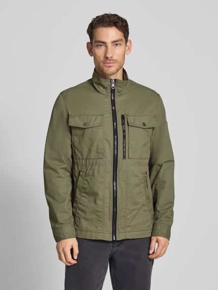 Männermodel trägt Regular Fit Jacke aus reiner Baumwolle von Tom Tailor in Olive, Two-Tone-Optik, Reißverschluss, Brust- und Seitentaschen, Ganzkörperansicht von vorne.