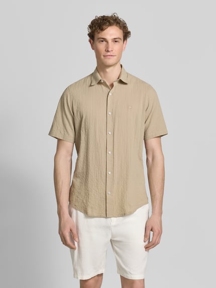 Mannenmodel draagt Relaxed Fit vrijetijdsoverhemd met logostitching en kentkraag van Lerros in seersucker, knoopsluiting, afgeronde zoom, ruglengte maat M 75 cm, schouderbreedte 45 cm, mouwlengte 25 cm, zandkleurig boven wit short, frontaal volledige lichaamsweergave.
