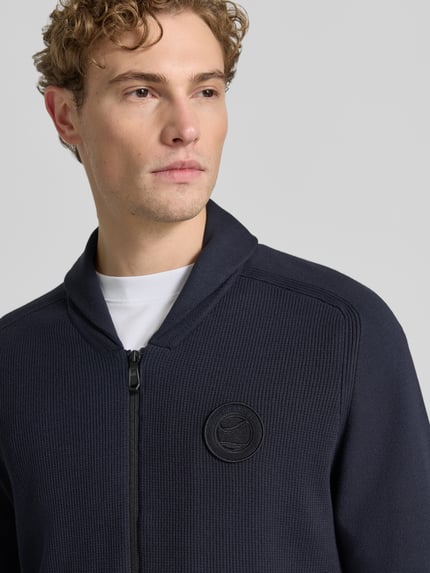 Männermodel trägt Regular Fit Strickjacke aus Viskose-Mix Modell 'KN_UNION FZ' von BOSS Green, dunkelblau, strukturierte Oberfläche, Nahaufnahme Oberkörper.