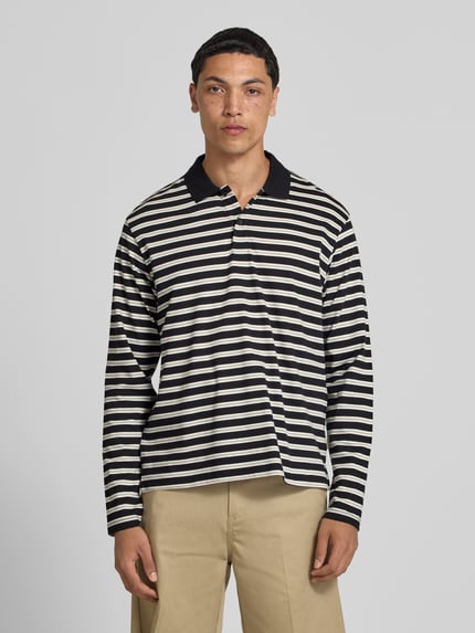 Männermodel trägt Regular Fit Poloshirt mit Streifenmuster Modell 'CASSIS' von Jack & Jones, Reine Baumwolle, Longsleeve, Knopfleiste, Rückenlänge bei Größe M 66 cm, dunkle und helle Streifen, Ganzkörperansicht von vorne.