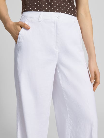 Frauenmodel trägt Leinenhose mit Eingrifftaschen Modell 'ADRIENNE' von Cambio aus Baumwolle-Leinen-Mix, ausgestellter Schnitt, Nahaufnahme Oberkörper. Bundweite bei Größe 36: 44 cm, Innenbeinlänge 83 cm, Knopf- und Reißverschluss, französische Eingrifftaschen, Gesäßtaschen.