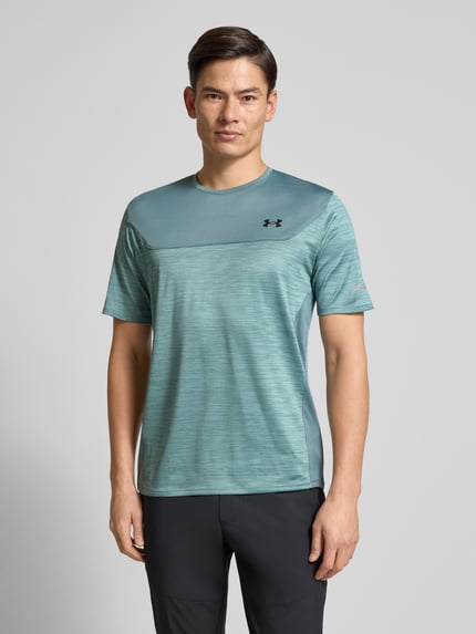Männermodel trägt Funktionsshirt mit Logo und Rundhalsausschnitt von Under Armour, Material-Mix mit Stretch-Anteil, Regular Fit, Ganzkörperansicht von vorne. Rückenlänge bei Größe M: 71 cm.