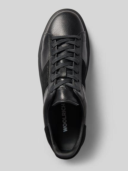 Produktfoto, Sneaker aus echtem Leder Modell 'Classic Court' von Woolrich, schwarze strukturierte Oberfläche, Schnürverschluss, strukturierte Sohle, abgerundete Form, Kontrastbesatz mit Label-Schriftzug, Absatzhöhe 4 cm, Schafthöhe 8 cm, Schaftweite 9 cm, Ansicht von oben.