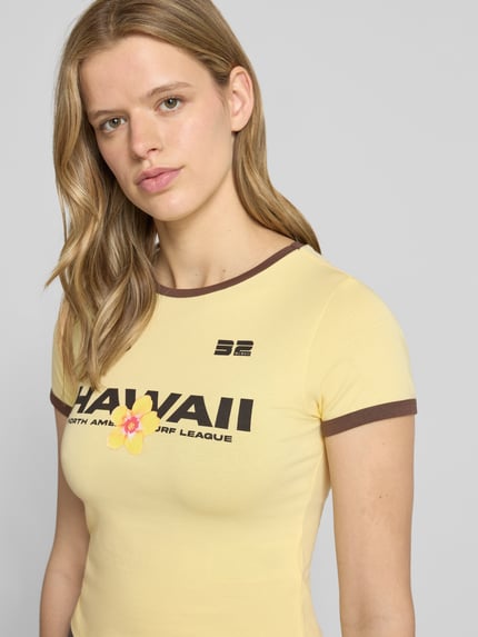 Frauenmodel trägt Slim Fit T-Shirt mit Statement-Print Modell 'Molly' von Noisy May, gelb mit braunen Details, elastischer Baumwoll-Mix, Nahaufnahme Oberkörper.