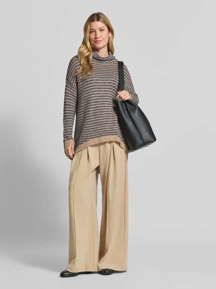 Frauenmodel trägt Oversized Fit Strickpullover mit Viskose-Anteil von Apricot, beige-braune Streifen, gerippte Abschlüsse, Ganzkörperansicht von vorne.