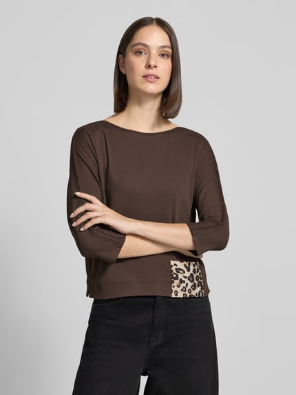 Frauenmodel trägt 3/4-Shirt mit seitlichem Patch-Detail von MARC CAIN, braune Unifarbe, Animal Print Akzent, Jersey, Nahaufnahme Oberkörper.
