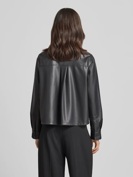 Frauenmodel trägt Relaxed Fit Hemdjacke in Leder-Optik Modell 'Zeather' von Someday in Schwarz mit Umlegekragen und Knopfleiste, Rückenlänge bei Größe 36: 52 cm, Schulterbreite: 40 cm, Brustweite: 65 cm, Ärmellänge: 63 cm, glatte Oberfläche, Ganzkörperansicht Rückansicht.