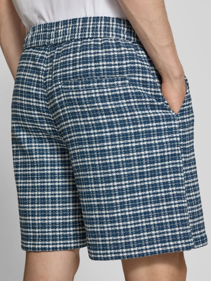 Männermodel trägt Shorts mit Strukturmuster Modell 'Kander' von Carhartt Work In Progress in Blau-Weiß, Paspeltasche, Ganzkörperansicht Rückansicht