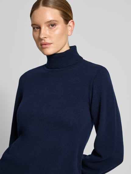 Frauenmodel trägt Strickpullover aus reiner Wolle Modell 'Jola' von My Essential Wardrobe, Woll-Mix, Rollkragen, dunkelblaue Farbe, taillierte Passform, Nahaufnahme Oberkörper.