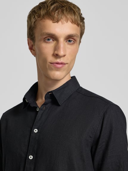 Männermodel trägt Slim Fit Leinenhemd mit Viskose-Anteil Modell 'Bobby' von Blend in Schwarz, sichtbarer Kentkragen und Knopfleiste, Nahaufnahme Oberkörper. Leinen-Mix, Kurzarm, modernes Design.
