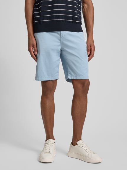 Mannenmodel draagt Tapered Chinoshorts aus Baumwoll-Mix van BOSS Orange in lichtblauw, twill, 5-pocket, elastische taille, voorkant volledige lichaamsopname.