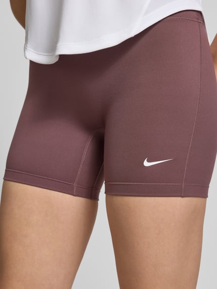 Frauenmodel trägt Radlerhose mit Logo und elastischem Bund von NIKE TRAINING, Material-Mix mit Stretch-Anteil, körpernahe Passform, Ganzkörperansicht von vorne.