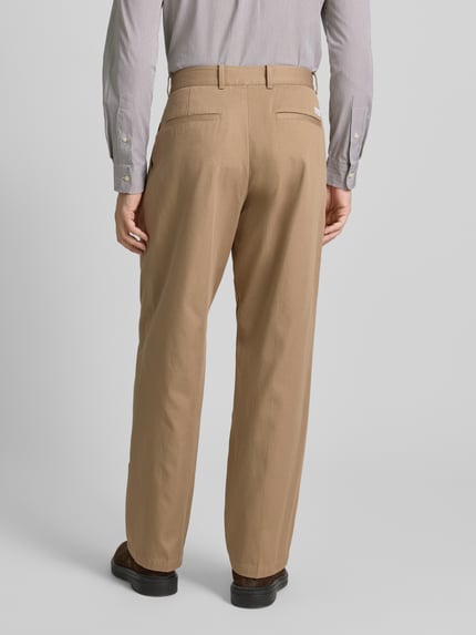 Männermodel trägt Wide Fit Bundfaltenhose aus reiner Baumwolle von Tommy Hilfiger in Beige, Mid Waist, 5-Pocket-Design, Ganzkörperansicht Rückansicht.