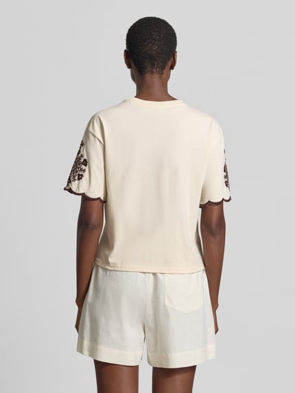 Frauenmodel trägt T-Shirt mit Wellensaum und Motiv-Stitching von Jake*s Casual in Creme mit braunen Ziernähten, reine Baumwolle, gerader Schnitt, Ganzkörperansicht Rückansicht.