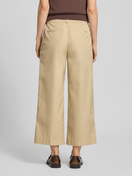 Frauenmodel trägt Hose in verkürzter Passform mit Eingrifftaschen von Gant aus Reine Baumwolle, Paspeltaschen am Gesäß, Ganzkörperansicht Rückansicht.