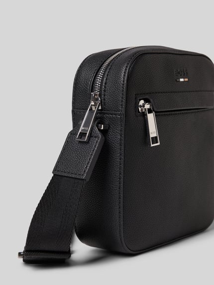 Produktfoto, Crossbody Bag mit Label-Detail Modell 'Ray' von BOSS, czarny materiał z fakturowanym wzorem, główna przegroda na zamek błyskawiczny, regulowany pasek na ramię, przegródka zapinana na zamek błyskawiczny z przodu, szerokość 17 cm, długość 19 cm, głębokość 6 cm, długość paska na ramię 120 cm.