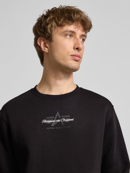 Männermodel trägt Regular Fit Sweatshirt aus Baumwoll-Mix mit Label-Detail von Alpha Industries, Schwarz, Nahaufnahme Oberkörper.
