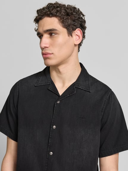 Männermodel trägt Regular Fit Jeanshemd aus Baumwolle von Diesel in Schwarz mit durchgehender Druckknopfleiste und Reverskragen, Nahaufnahme Oberkörper. Kurzärmeliges Herren Freizeithemd aus Reiner Baumwolle, Regular-Fit, Rückenlänge 72 cm, Schulterbreite 44 cm, Ärmellänge 31 cm.