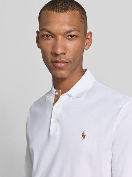 Männermodel trägt Slim Fit Poloshirt aus reiner Baumwolle von Polo Ralph Lauren in Weiß mit glatter Textur, Nahaufnahme Oberkörper.